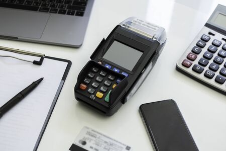 Top view credit card machine with calculator laptop credit card smartphone paperwork and pen on the white table. Cashless paying for shopping concept. Buy and sell products & service conceptの写真素材