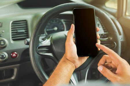 A man using a smartphone in his carの写真素材