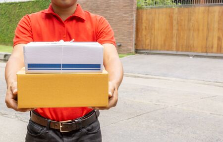 Deliveryman in red uniform holding package courier with parcel. Delivery conceptの写真素材