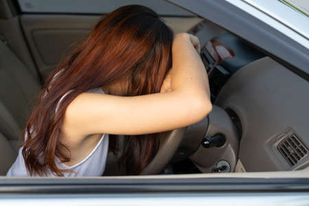 Closeup portrait sleepy tired fatigued exhausted young woman long hair driving her car in street...