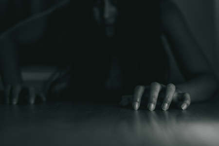 Female ghost in white dress in room. A young scary girl in an old white dress staring in to the camera ferociously with dark background. Asian woman make up ghost face at house. Scary horror concept.の写真素材