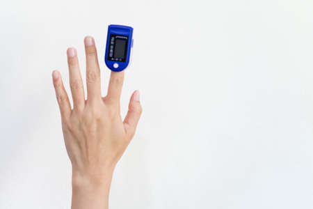 Hands female using pulse oximeter device on finger.on white isolate background. Healthcare monitoring conceptの写真素材