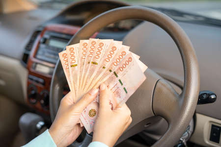 Hands woman holding banknote in new car . Hands female of take money sitting in her car prepare pay...