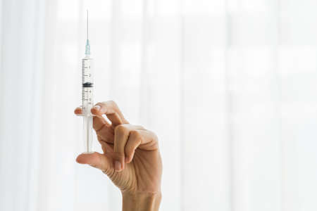 Closeup hand holding syringe at the clinic office. Medicare concept, Vaccination concept.