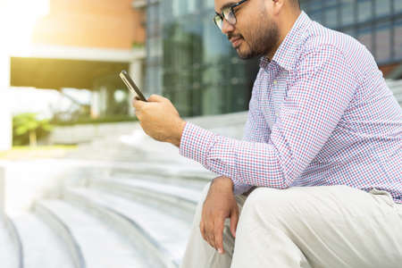 Bearded businessman smiling wearing glasses using modern smartphone device typing text message in...