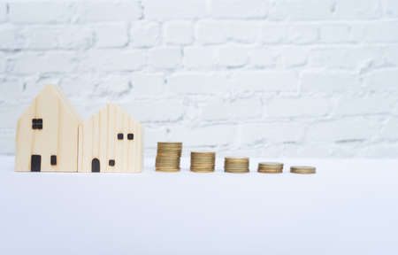 Wooden house and money coin stack  on white table. Financial conceptの写真素材