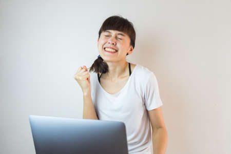 A woman smiling using laptop computer and celebrating successの写真素材