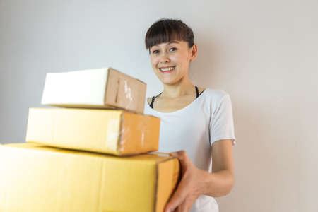 Asian woman smiling carrying three cardboard boxes. Startup small business conceptの写真素材