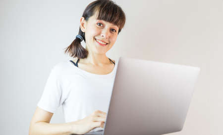 A woman smiling looking camera using laptop computer celebrating success.の写真素材