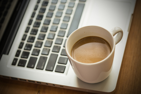 Hot latte coffee cup and laptop on wood background and texture.の写真素材