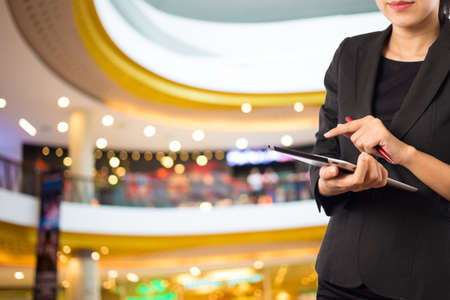 Women in shopping mall using mobile Tablet PC.の写真素材