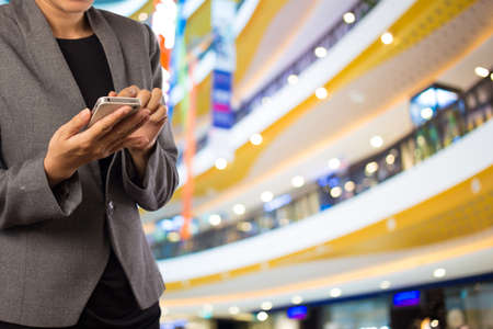 Women in shopping mall using mobile phone.の写真素材