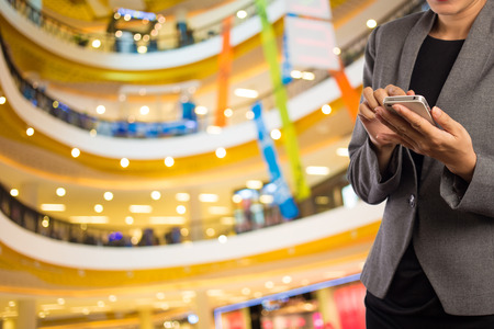 Women in shopping mall using mobile phone.の写真素材