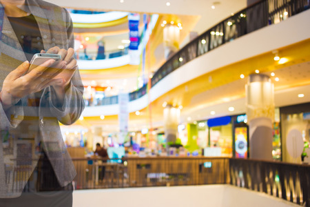 Women in shopping mall using mobile phone.の写真素材