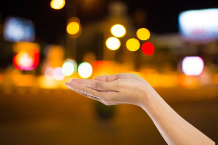 Women hand  on City night light blur bokeh , bokeh background.の写真素材