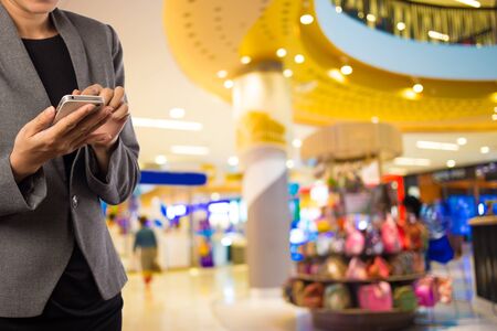 Women in shopping mall using mobile phone.の写真素材