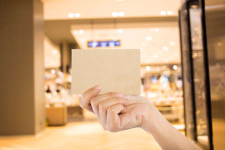 Photo blank. Hand hold blank business card in the shopping mall.
