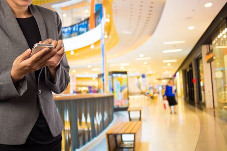 Businesswoman using smart phone in shopping mall.の写真素材