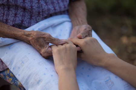 Old and young holding hands on light background, closeupの写真素材