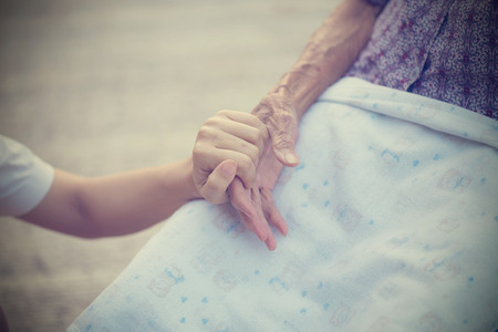 Old and young holding hands on light background, vintage tone.の写真素材