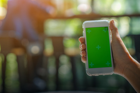 The view is cut out of the woman's hand holding a smart phone with a blank screen for text message...