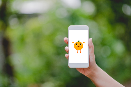 Hands and phones Cute little orange screen Green nature Technology Concepts And to do business online.の写真素材