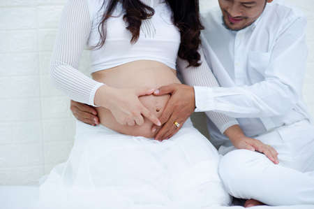 The pregnant woman is happy with her husband, preparing to watch the child who is about to give...