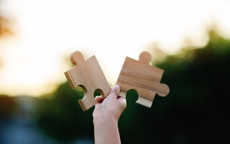 Jigsaw in hand, a puzzle piece that is critical to success. Creativity, ideas, initiative, unity, teamworkの写真素材