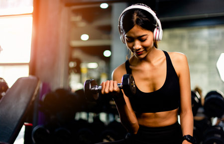 lifting dumbbells arm exercises Young woman wearing headphones while exercising Create energy for exercise with exercise music, body weight exercises for a healthy body.の写真素材