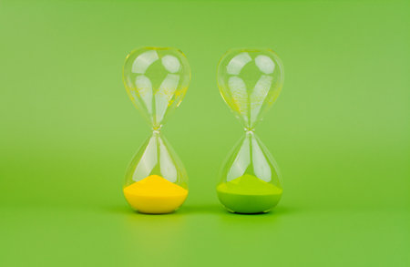 Green and yellow hourglass on a light green background, rules of time and countdown time process.