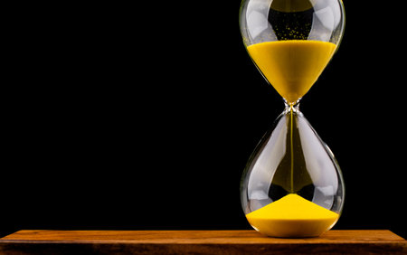 Hourglass stops time of work and life. Process and rules of limited time. Hourglass photo in studio.の写真素材