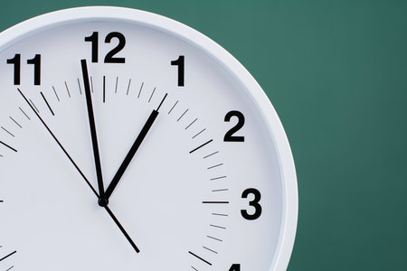 Clock telling time and working on time. Photo of clock in studio with green background.の写真素材