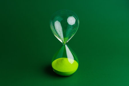 Hourglass and working with limited time, time constraints and countdown. Hourglass photo on green background.の写真素材