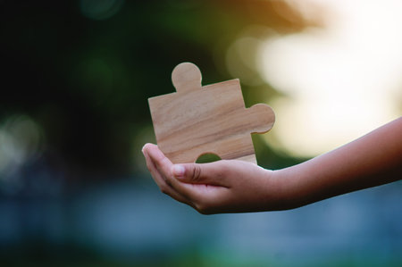 Wooden jigsaw puzzle in hand, cooperation and teamwork, good connection and coordination.の写真素材