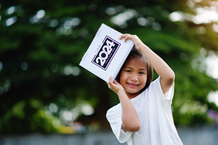 A cute little girl is holding a calendar, smiling happily, with a youthful and optimistic outlook. The girl's eyes are sincere.の写真素材