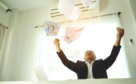 Successful business people throwing papers celebrating and enjoying their work, working on financial documents.の写真素材