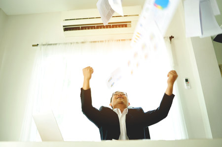 Successful business people throwing papers celebrating and enjoying their work, financial planning and investing, working on financial documents.の写真素材