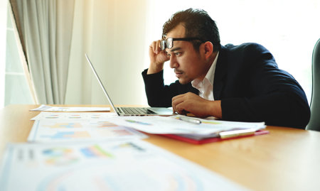 Emotional state, work-related problems and accumulated stress, anxiety. Businessman at a desk with documents.の写真素材