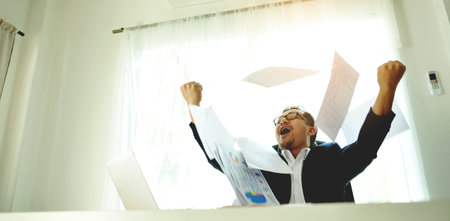 Successful business people throwing papers celebrating and enjoying their work, financial planning and investing, working on financial documents.の写真素材