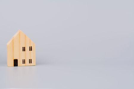 A small wooden house against a gray background, reflecting concepts of home and relocation.の写真素材