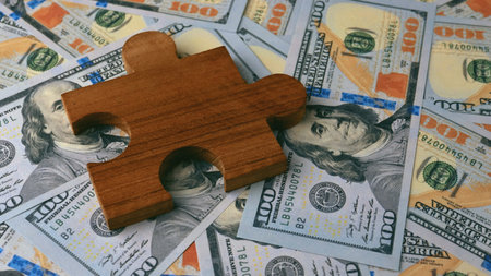 Dollar currency and wooden jigsaw puzzle, financial investment, income and cash flow, financial success goals.の写真素材