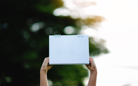 The image depicts a blank white sheet of paper, hands raised in a gesture of victory and success in work, and a free and relaxed life in harmony with nature.の写真素材