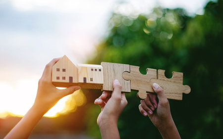 The house and wooden jigsaw puzzle, bathed in sunlight, sparkle with the powerful image of cooperation and teamwork.の写真素材