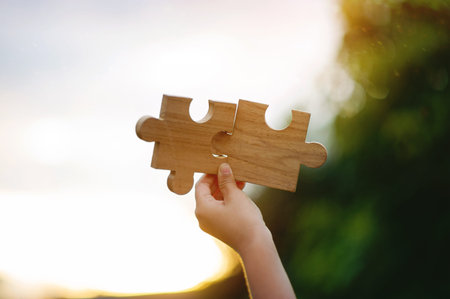 The wooden jigsaw puzzle and sparkling sunlight powerfully represent cooperation and teamwork.の写真素材