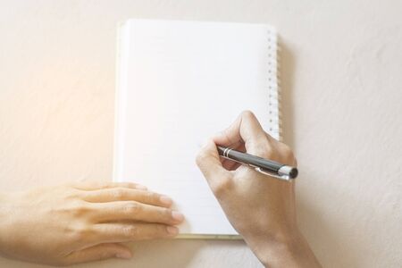 Women holding a pen writing a notebook. Recording concept