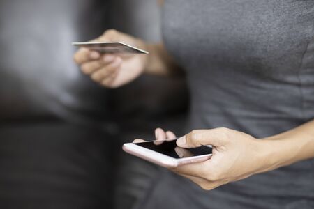 Hands of Women playing a smart phone she is shopping online via credit cards. Business and...