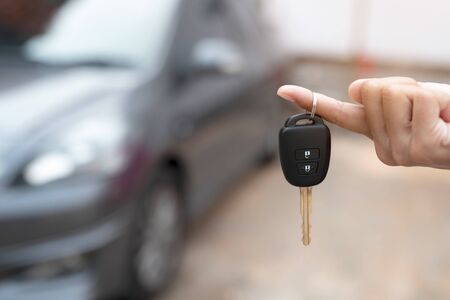 Close up of dealer giving key to new owner and shaking hands in auto show.auto business, car sale,...