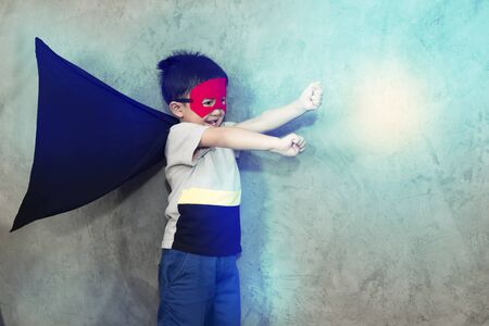 The boy dressed up in a superhero outfit, pretending to fight in studio,has light effect.Boy power concept And development of young children.の写真素材