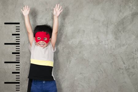 The boy in the superhero outfit smiled and raised his hand to show the growth, with a unit beside...