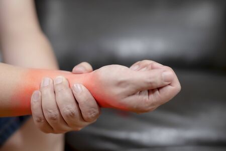 A young man with pain in his hand because of hard work, Ache in human body , office syndrome,Bone and joint disease, Concept healthcare and medical.の写真素材